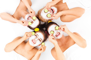 A picture of four friends enjoying their time in spa with facial masks over white background