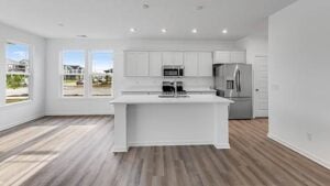 Bright kitchen in Hobbs Station’s Gallium model with natural light, white cabinetry, and center island