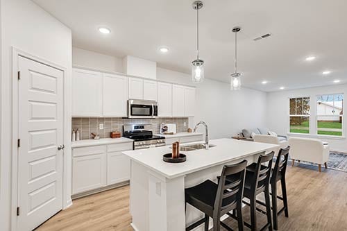 Modern kitchen layout with center island and bar seating in 3-bedroom Metro model townhome at Colonnade