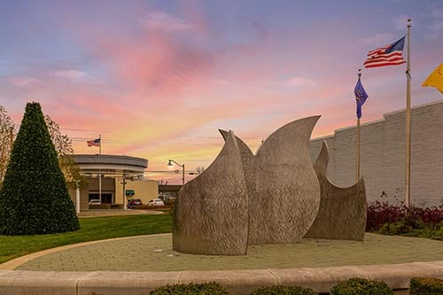 Public art sculpture and flags in Mooresville’s community plaza at sunset, highlighting local culture