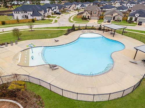 Resort-style pool with shaded areas and splash feature in Raburn Reserve, offering luxury living in Tomball